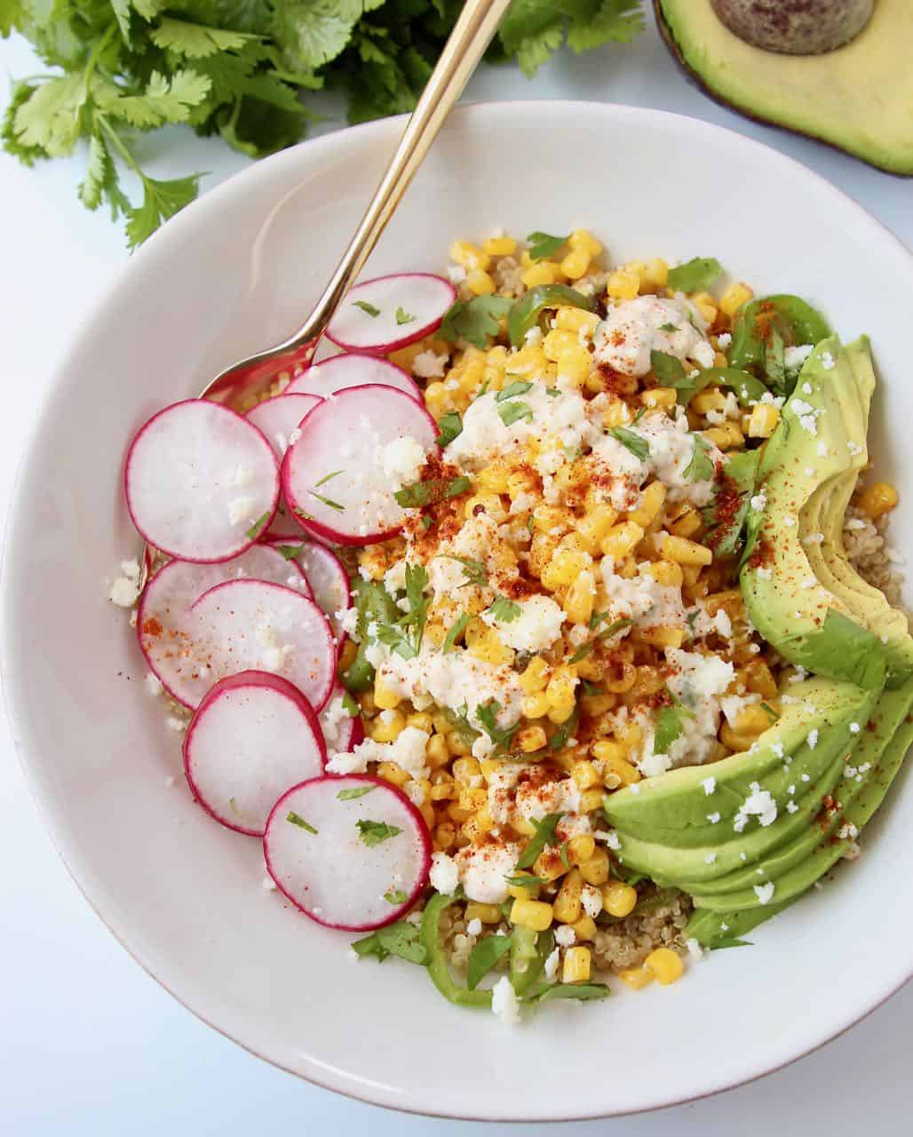 Bowl filled with corn, avocado, radishes and cilantro