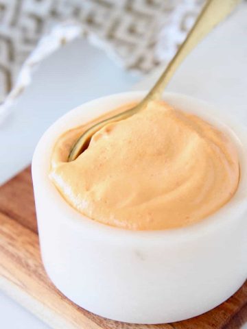 Harissa tahini sauce in small bowl with gold spoon