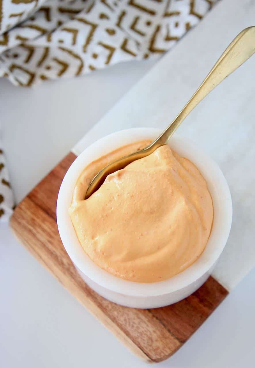 Overhead image of harissa tahini sauce in small bowl with spoon