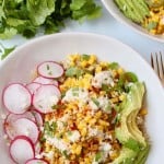 Overhead image of corn in bowl with sliced avocado and radishes