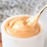 Harissa tahini sauce in white bowl with gold spoon