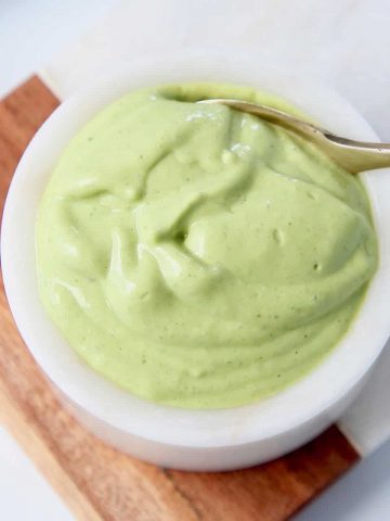 Overhead shot of creamy avocado dressing in bowl with spoon