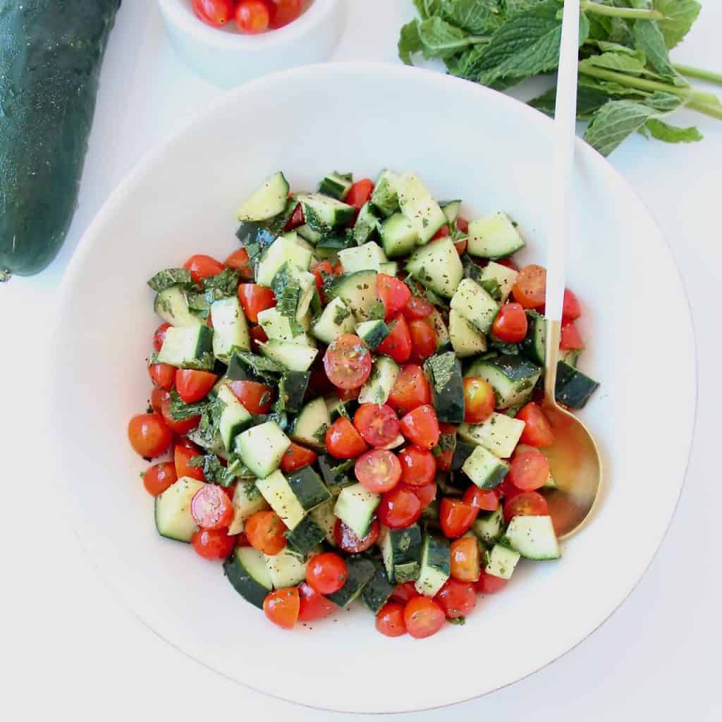 Diced cucumber tomato salad in bowl with spoon