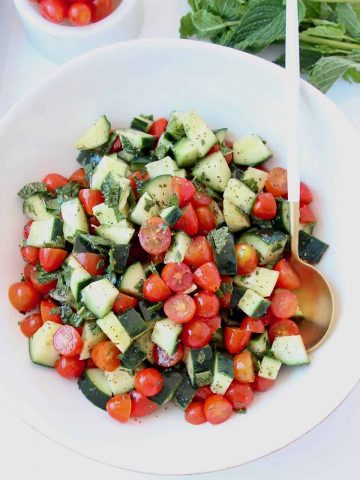 Diced cucumber tomato salad in bowl with spoon