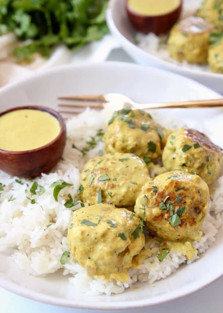 Meatballs covered in yellow curry sauce in bowl with rice