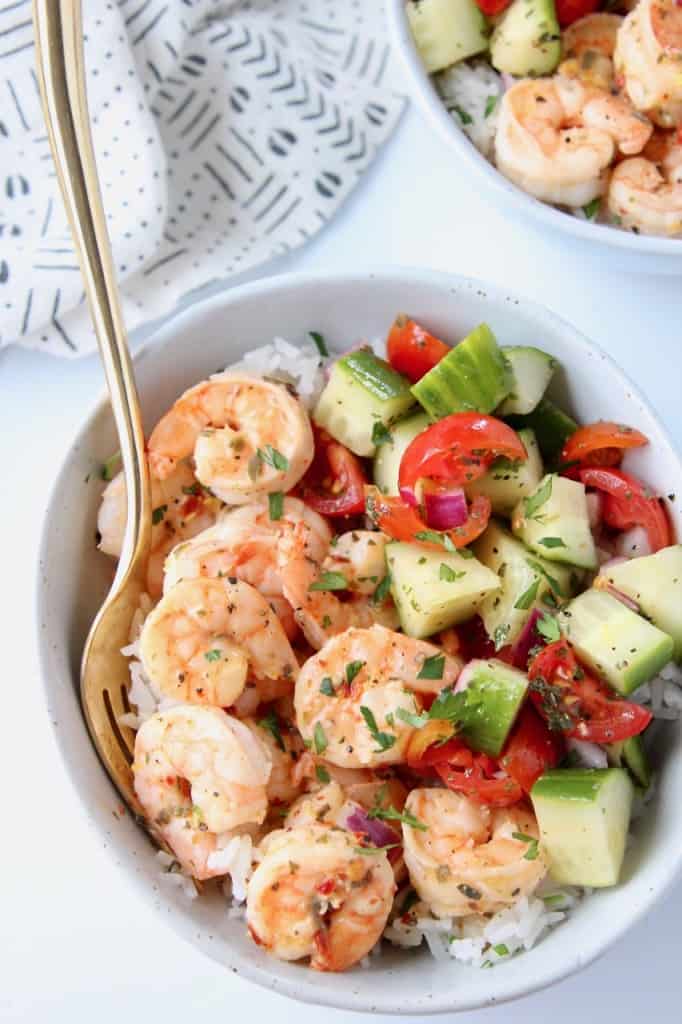 Overhead image of shrimp and tomato cucumber salad in bowls with rice