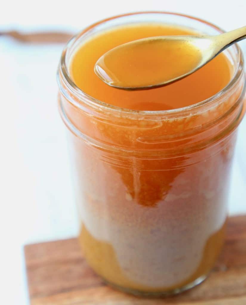 Mason jar full of miso vinaigrette dressing with spoonful of dressing coming out of the top