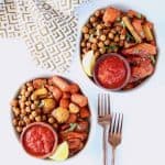 Overhead image of two bowls filled with chickpeas, carrots, tomatoes and lemon wedge