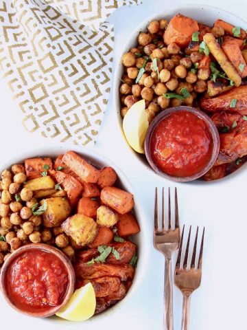 Overhead image of two bowls filled with chickpeas, carrots, tomatoes and lemon wedge