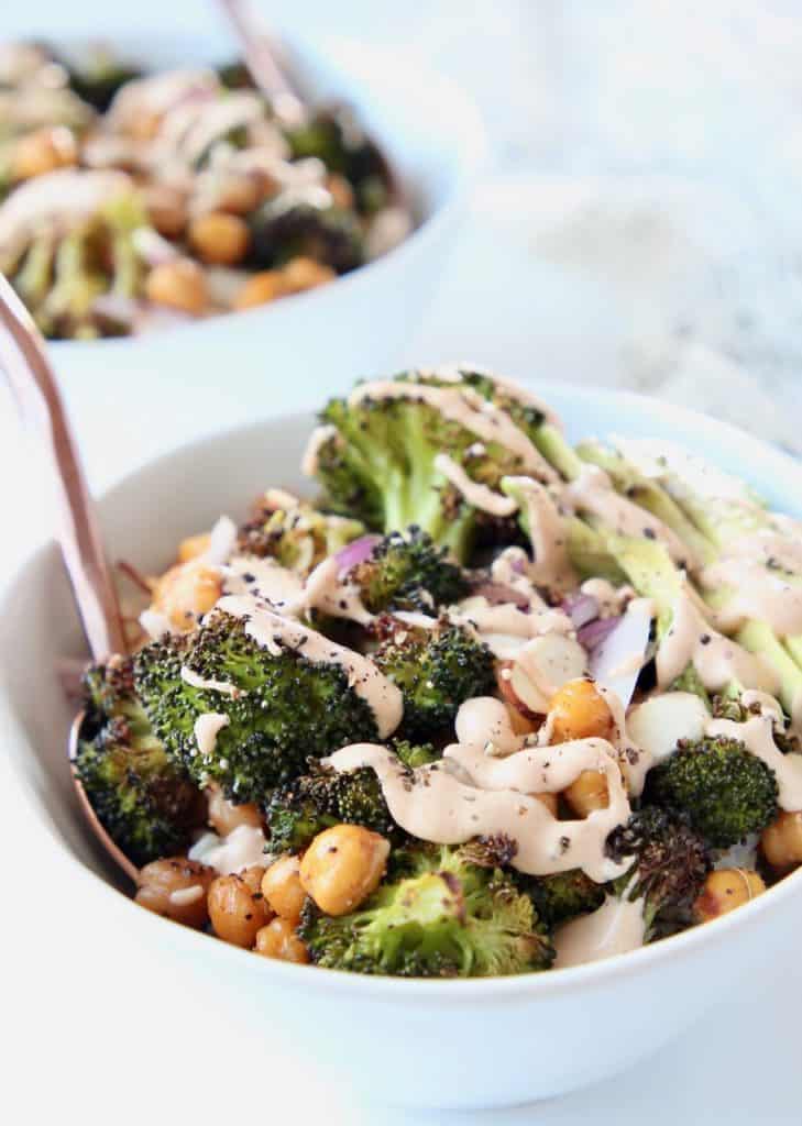 Roasted broccoli and chickpeas in white bowls with gold forks
