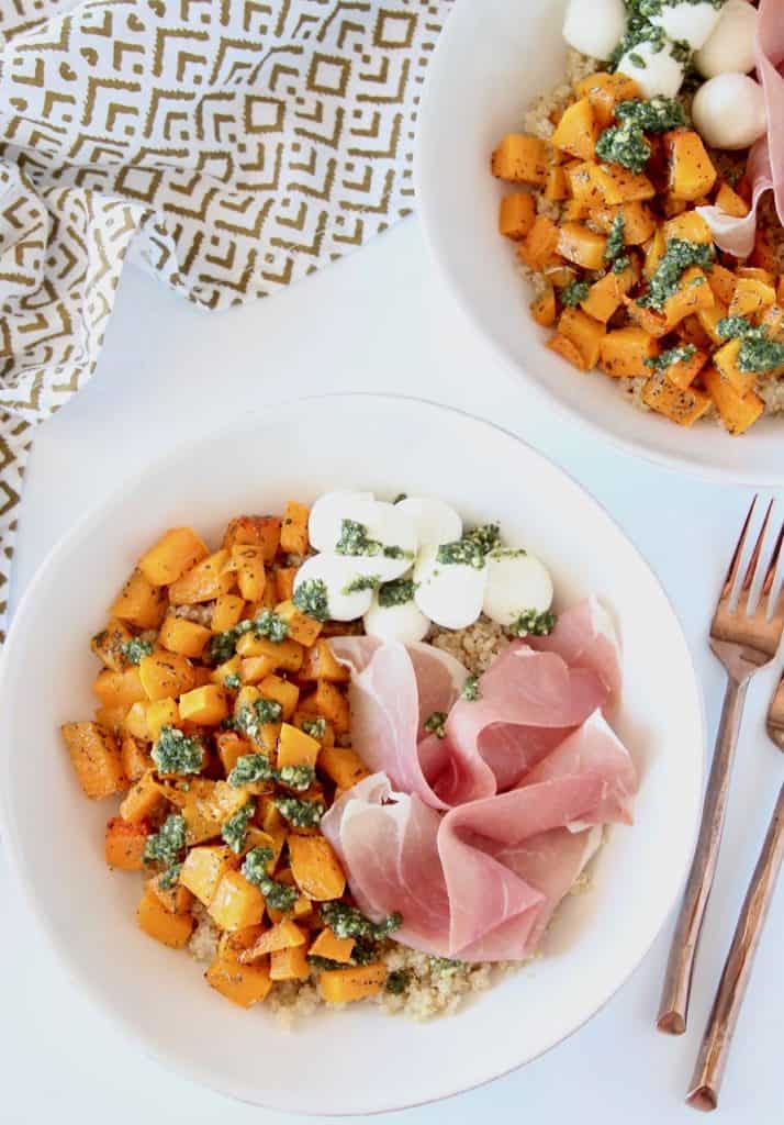 Overhead image of bowls filled with roasted butternut squash cubes, covered in basil pesto