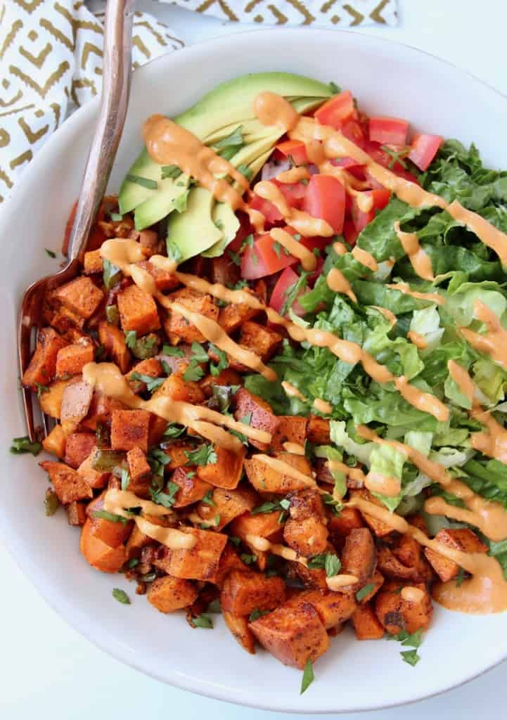 Overhead image of bowl with diced sweet potatoes, lettuce, tomatoes and avocado