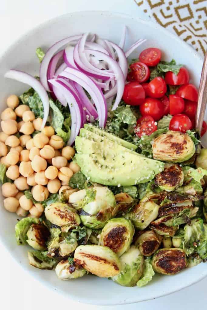 Cobb salad in bowl topped with brussels sprouts, garbanzo beans and avocado