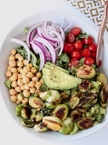 Overhead image of salad in bowl with roasted brussels sprouts, tomatoes and avocado