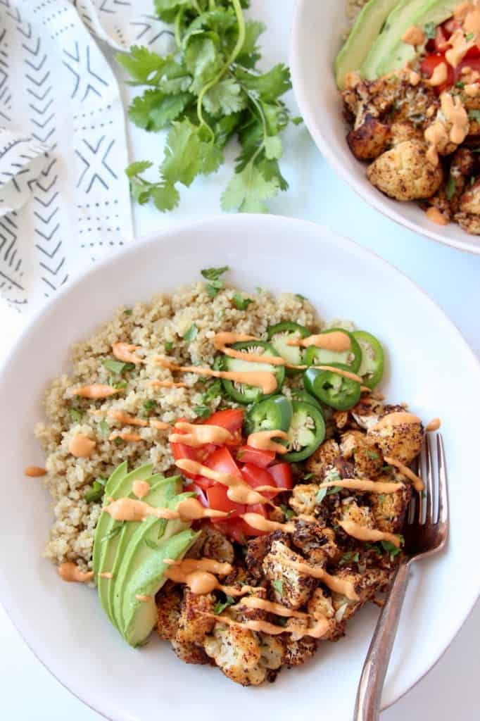 Overhead image of bowls filled with quinoa, sliced avocado and roasted cauliflower