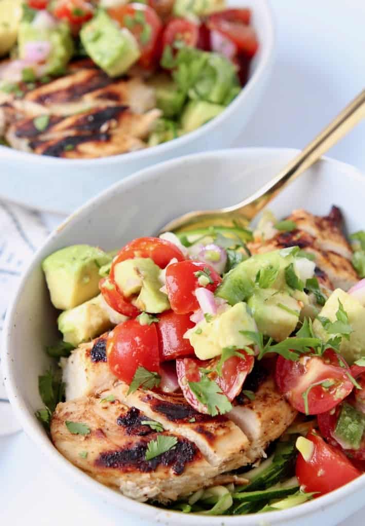 Sliced chicken in bowl topped with diced avocado salsa