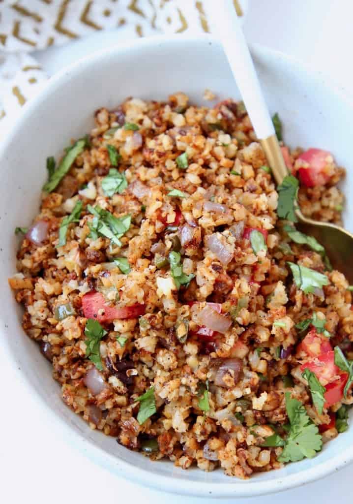 Roasted cauliflower rice in bowl with spices and tomatoes