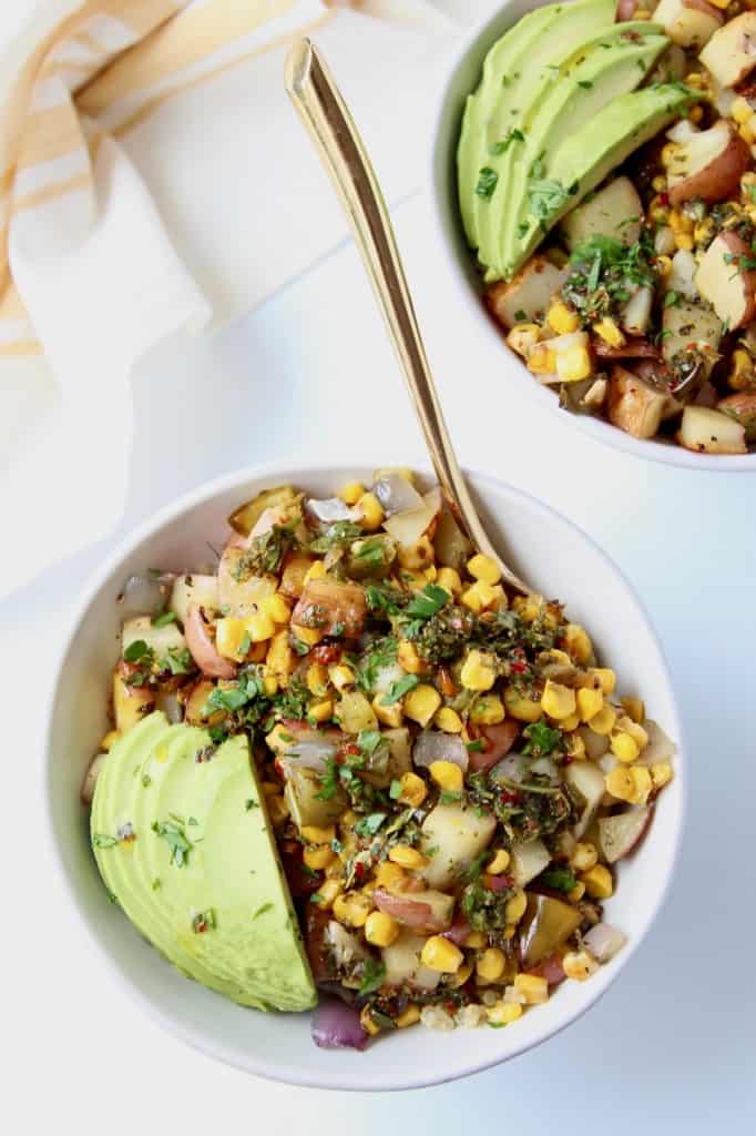 Overhead image of bowls with grilled vegetables and sliced avocado