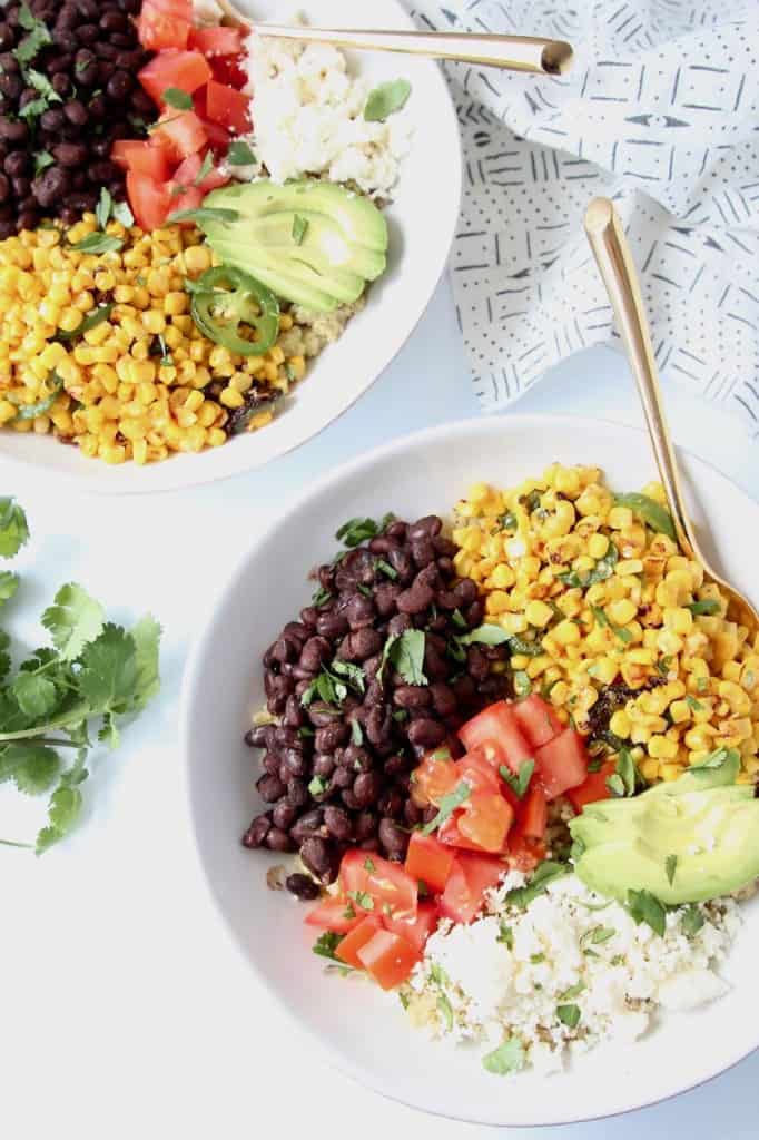 Overhead image of bowls filled with quinoa, beans, corn, tomatoes and avocado