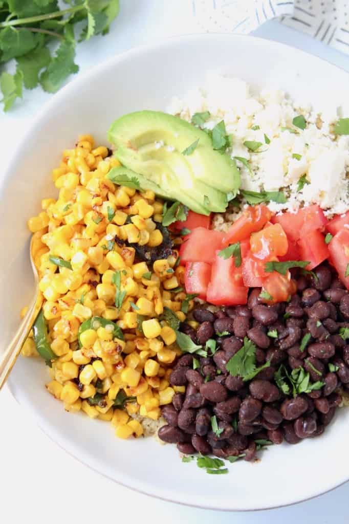 Overhead image of corn, beans, avocado and diced tomatoes in bowl