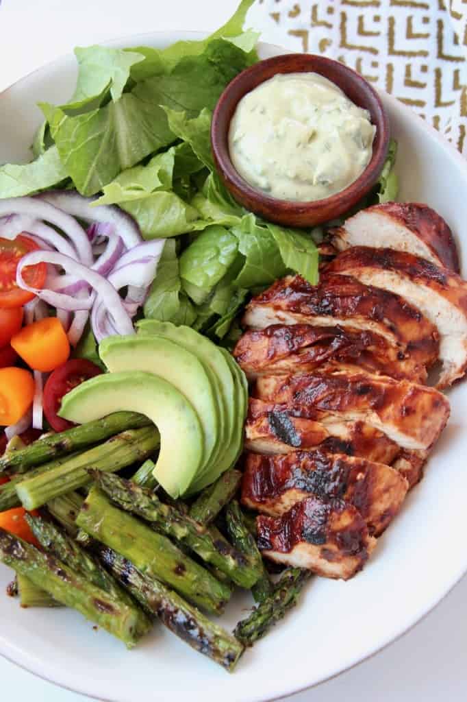 Sliced bbq chicken in bowl with salad