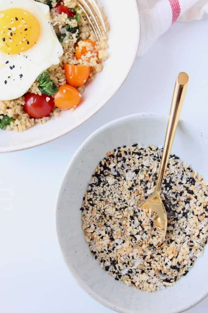 Everything bagel seasoning in bowl with gold fork next to bowl with egg