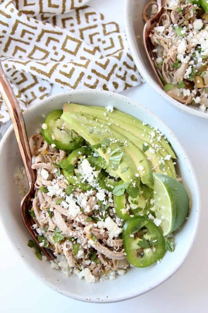 Overhead image of shredded pork in bowl with sliced avocado and jalapenos