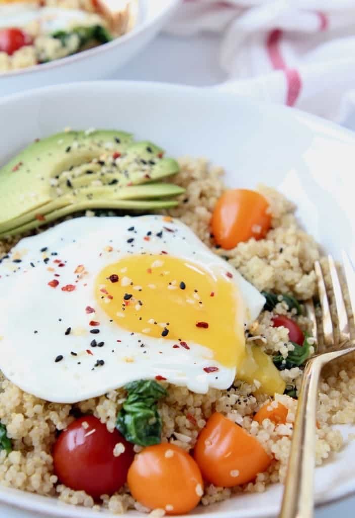 Sunny side up egg in bowl with quinoa, tomatoes and avocado