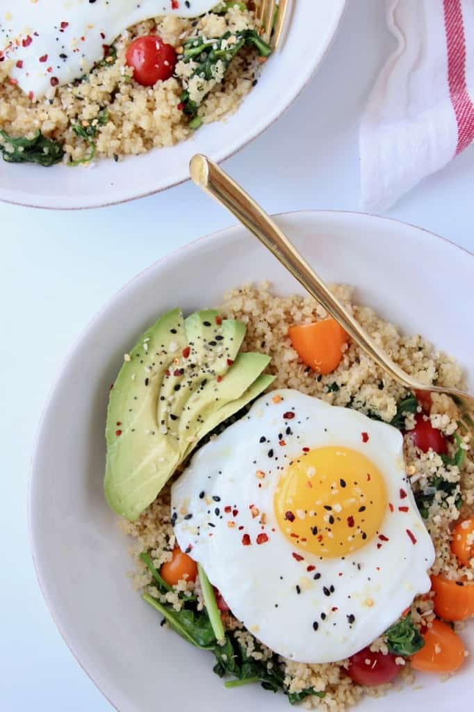Overhead image of fried egg on top of bowl of quinoa with sliced avocado