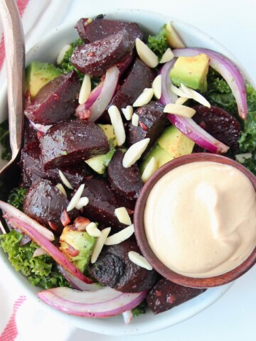 Overhead image of kale beet salad in bowl with side of tahini dressing