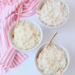 Three bowls of white rice with gold spoons