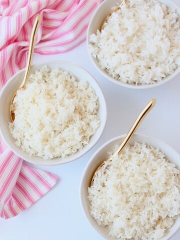 Three bowls of white rice with gold spoons