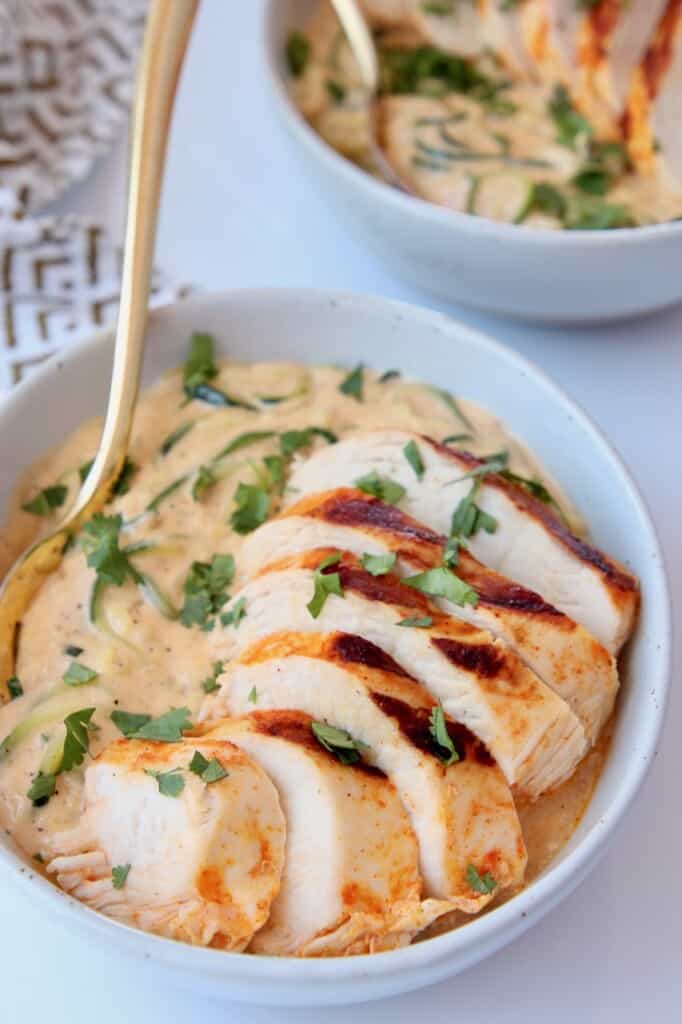 Sliced chicken breast in bowl with zucchini noodles in a cheese sauce