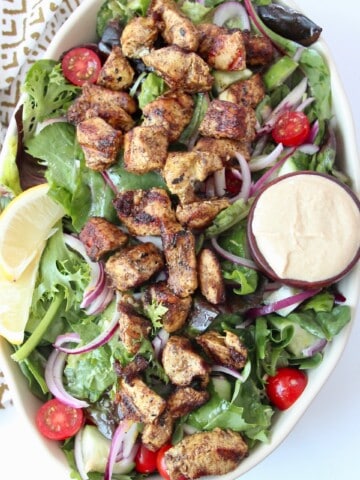 overhead image of grilled chicken on salad in bowl
