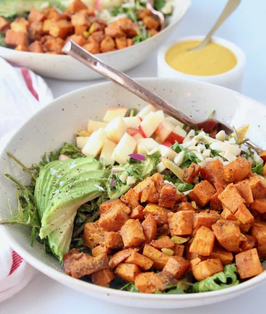 roasted diced sweet potatoes in salad bowl with sliced avocado and diced apples