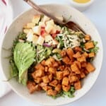 overhead image of kale sweet potato salad in bowl with sliced avocado and diced apples