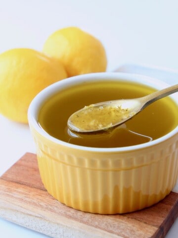lemon vinaigrette dressing in yellow bowl with small gold spoon in bowl