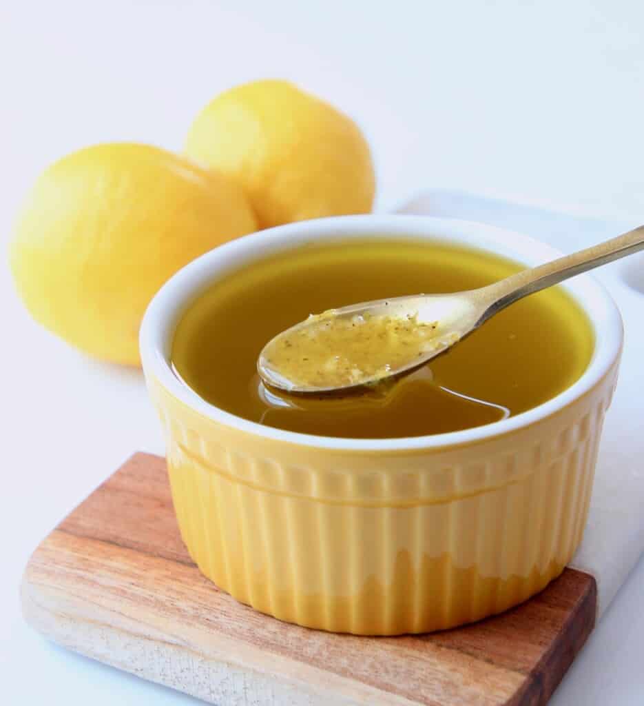 lemon vinaigrette dressing in yellow bowl with small gold spoon in bowl