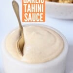 garlic tahini sauce in small marble bowl with gold spoon