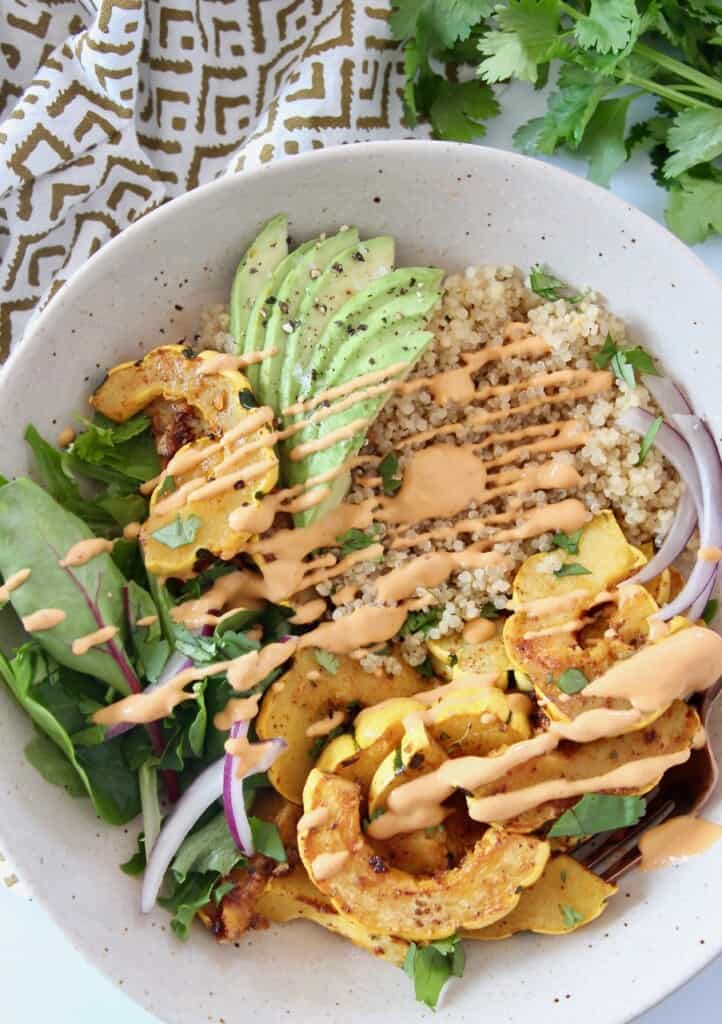 overhead image of roasted squash quinoa bowl drizzled with chipotle sauce