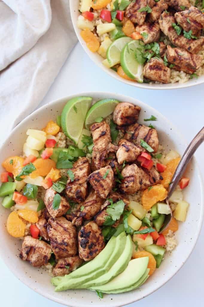 grilled chicken, diced pineapple and sliced avocado in bowls with copper fork and lime wedges