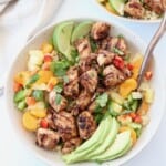 grilled pieces of chicken in bowl with diced fruit and peppers