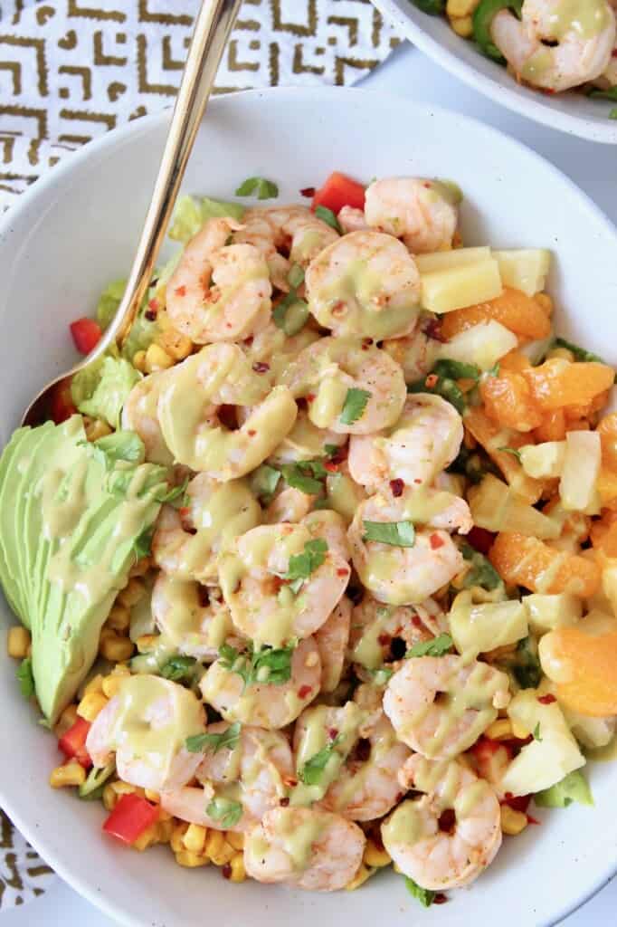 cooked shrimp on salad in bowl topped with honey lime salad dressing