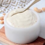 creamy garlic cashew sauce in small bowl with spoon
