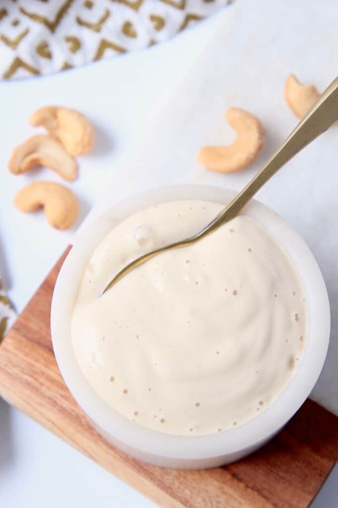 overhead image of garlic cashew cream sauce in bowl with small spoon