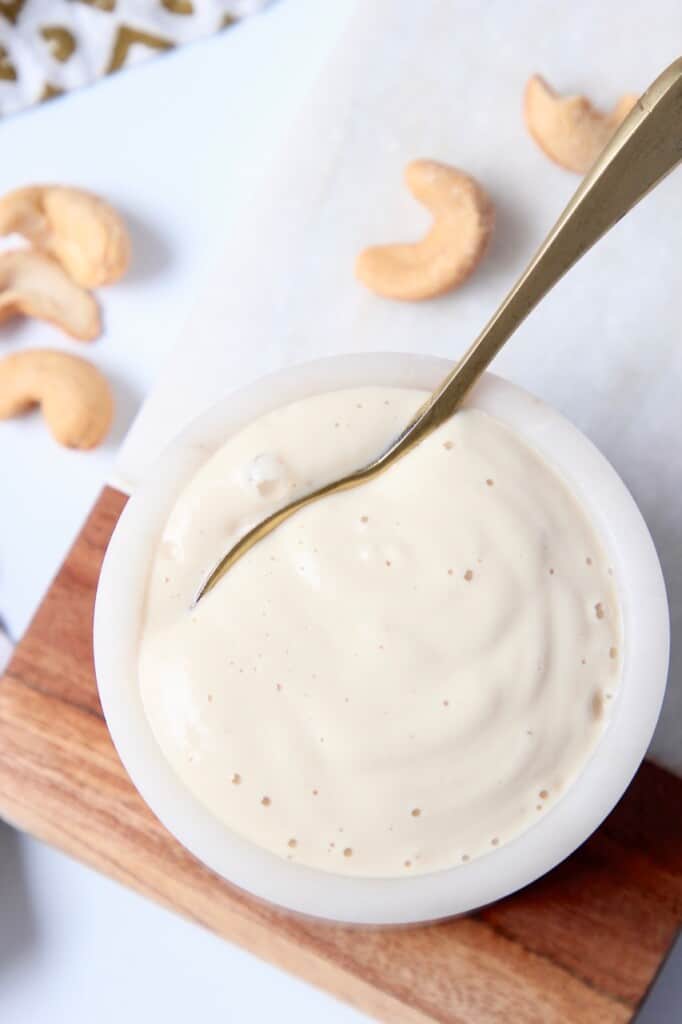 overhead image of garlic cashew cream sauce in bowl with small spoon