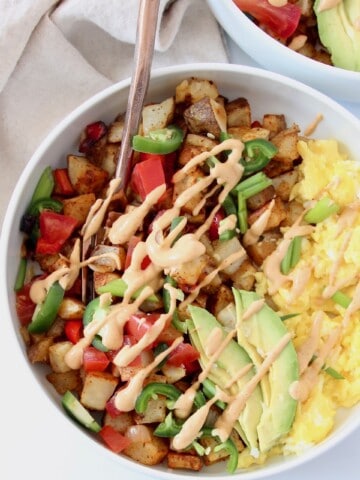 bowl filled with scrambled eggs, roasted potatoes and sliced avocado