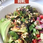 roasted broccoli in bowls with sliced avocado and diced tomato and cucumber salad