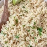 cooked quinoa tossed with cilantro in bowl with spoon and lime wedge