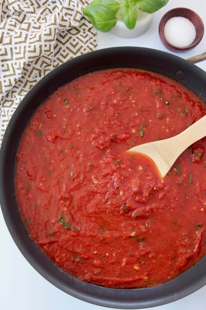marinara sauce in large skillet with wooden spoon